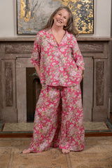 Melissa wearing pink floral pajamas standing in front of a fireplace.