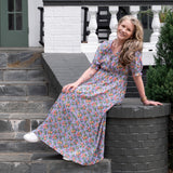 Melissa in a floral dress sitting on stone steps outside a house