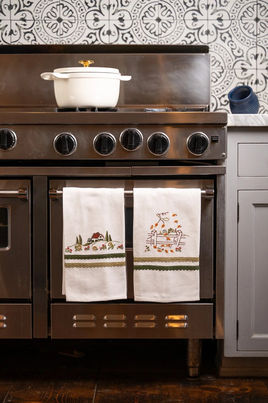 Embroidered tea towels hanging on an oven door